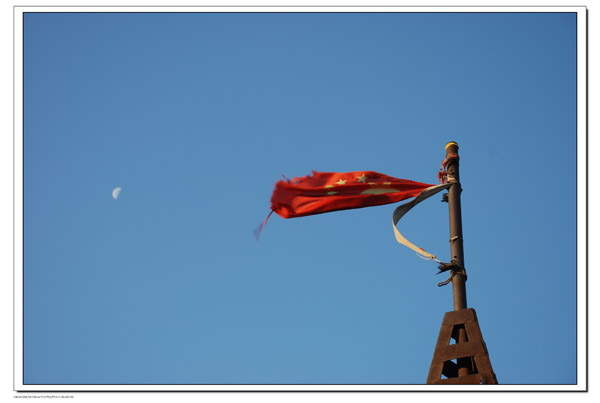 主峰上的五星红旗在日月同辉的早上，迎风招展